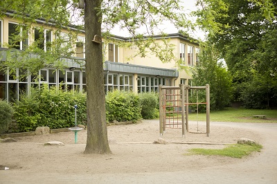 Schule mit Hecke und Klettergerüst