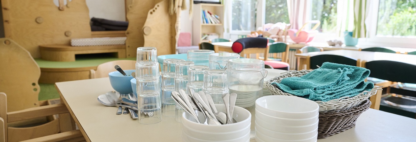 Ein Tisch in der Kita, auf der das Geschirr für das Essen steht.